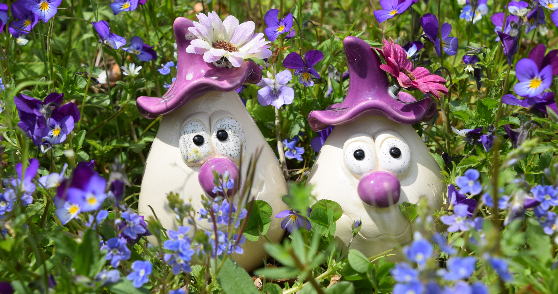 Handgemachte Tonwicht-Figuren im Blumenbeet